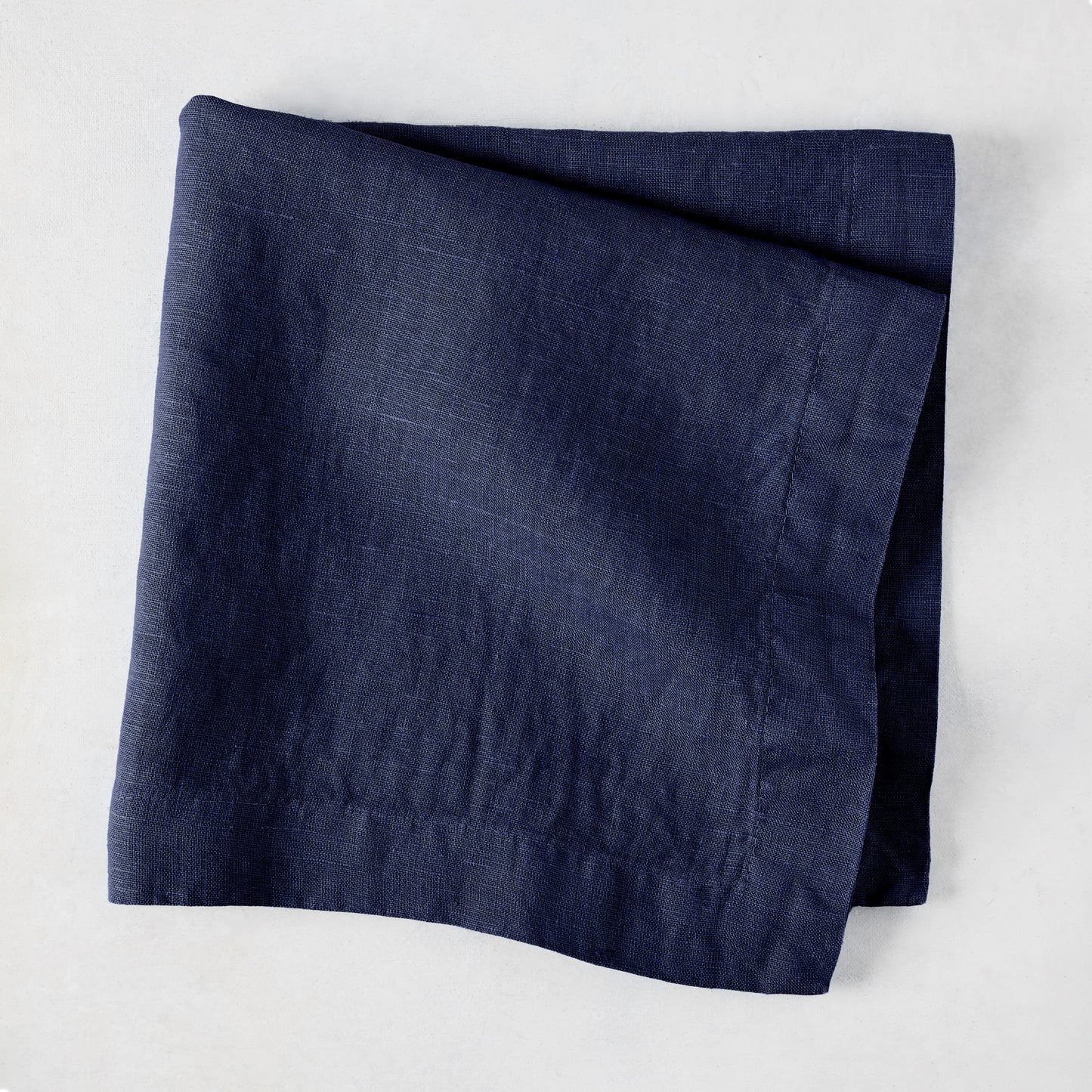 Folded Indigo HG Signature hand-dyed linen napkin, 22-inch square, with mitered corners.