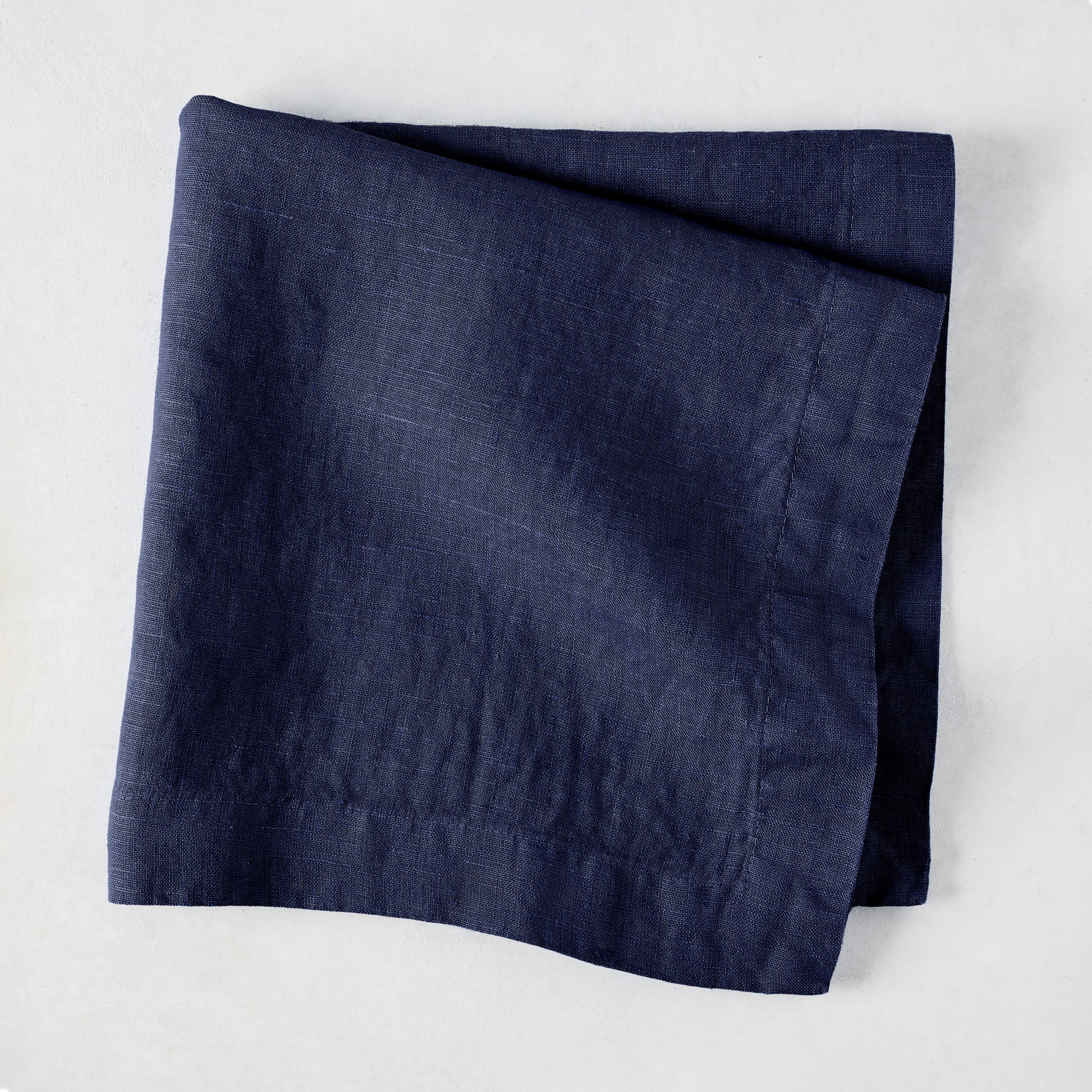 Folded Indigo HG Signature hand-dyed linen napkin, 22-inch square, with mitered corners.