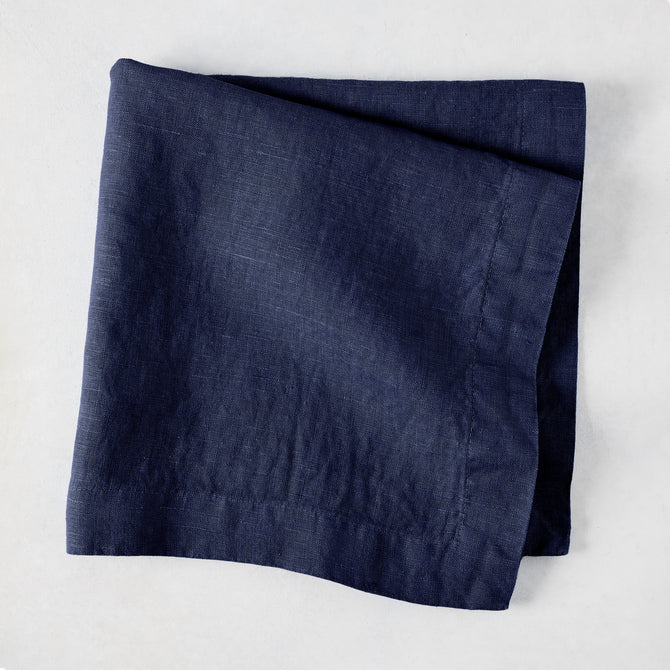 Folded Indigo HG Signature hand-dyed linen napkin, 22-inch square, with mitered corners.
