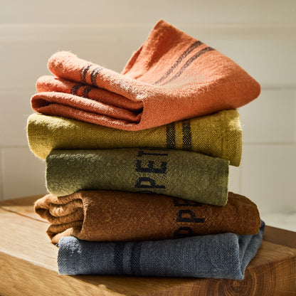 Stack of five folded French linen hand towels in various colors.
