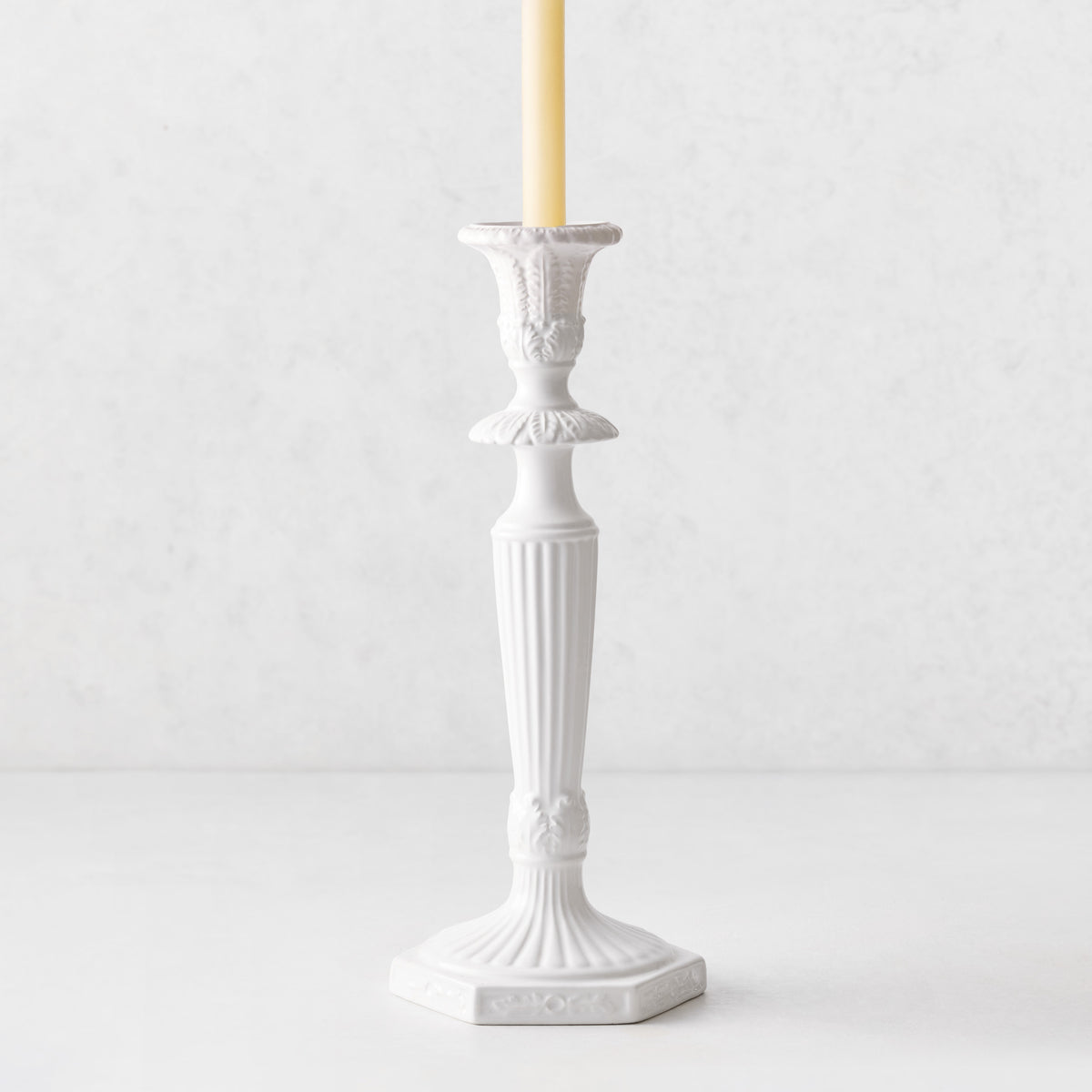 Small white Italian ceramic candlestick with intricate antique-style detailing and a taper candle.