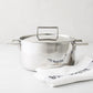 Italian 3-liter stainless steel casserole pot with lid and handles, beside a white "Bon Appetit" towel.