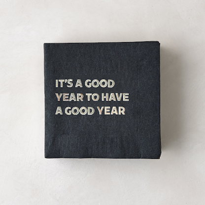 Black 5.5" square paper cocktail napkin with "It's a Good Year to Have a Good Year" in silver foil.