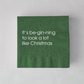 Dark green 3-ply paper cocktail napkin with white text reading It’s be-gin-ning to look a lot like Christmas.