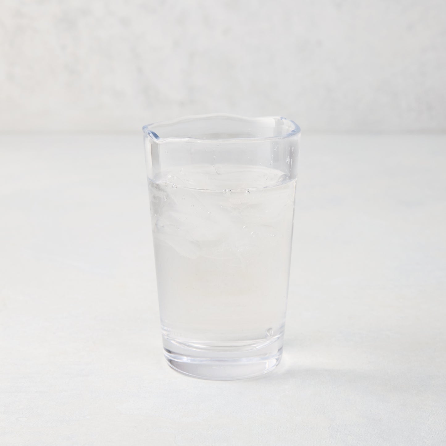 Jacob Scissor-Cut Glass Tumbler, 8 oz., clear, thick air-blown glass with rippled rim, filled with water and ice.