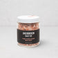 Jacobsen Salt Co. pink Himalayan salt crystals in a clear glass jar with a white lid and black label.