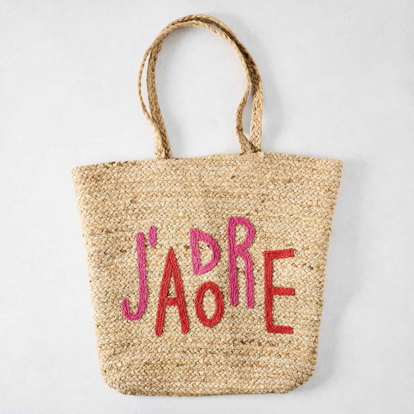 Natural jute woven tote bag with "J'ADORE" embroidered in red and pink.