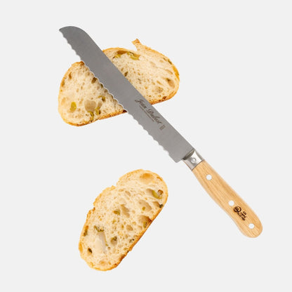 Jean Dubost bread knife with serrated stainless steel blade and light oak wood handle, next to two slices of bread.