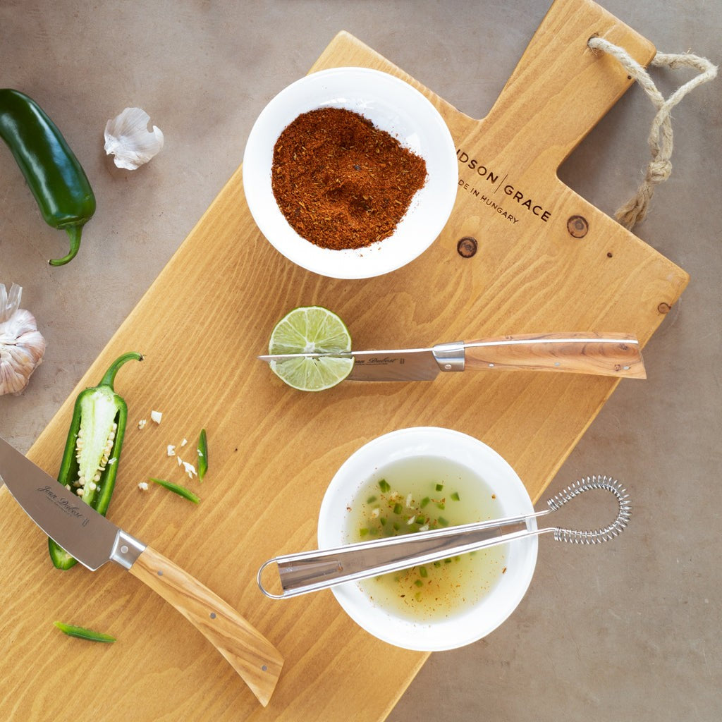 Jean Dubost Laguiole olive wood steak knives with stainless steel blades on a cutting board.