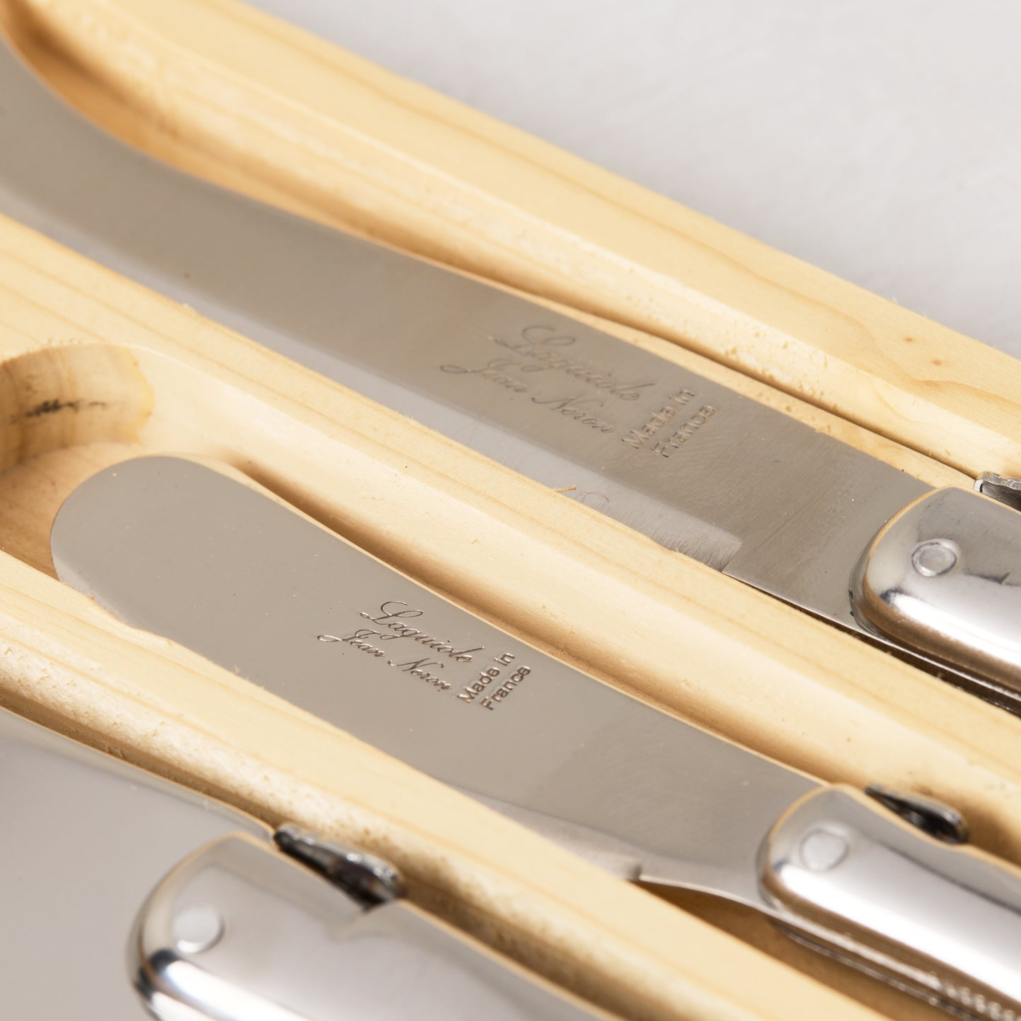 Jean Dubost Laguiole 3-piece stainless steel cheese knife set with brushed metallic handles in a wooden box.