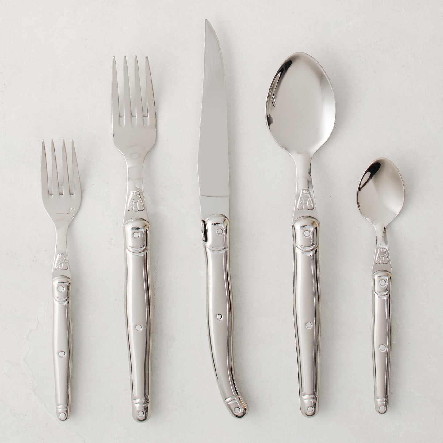 Jean Dubost Laguiole 5-piece stainless steel flatware set with iconic bee emblem.
