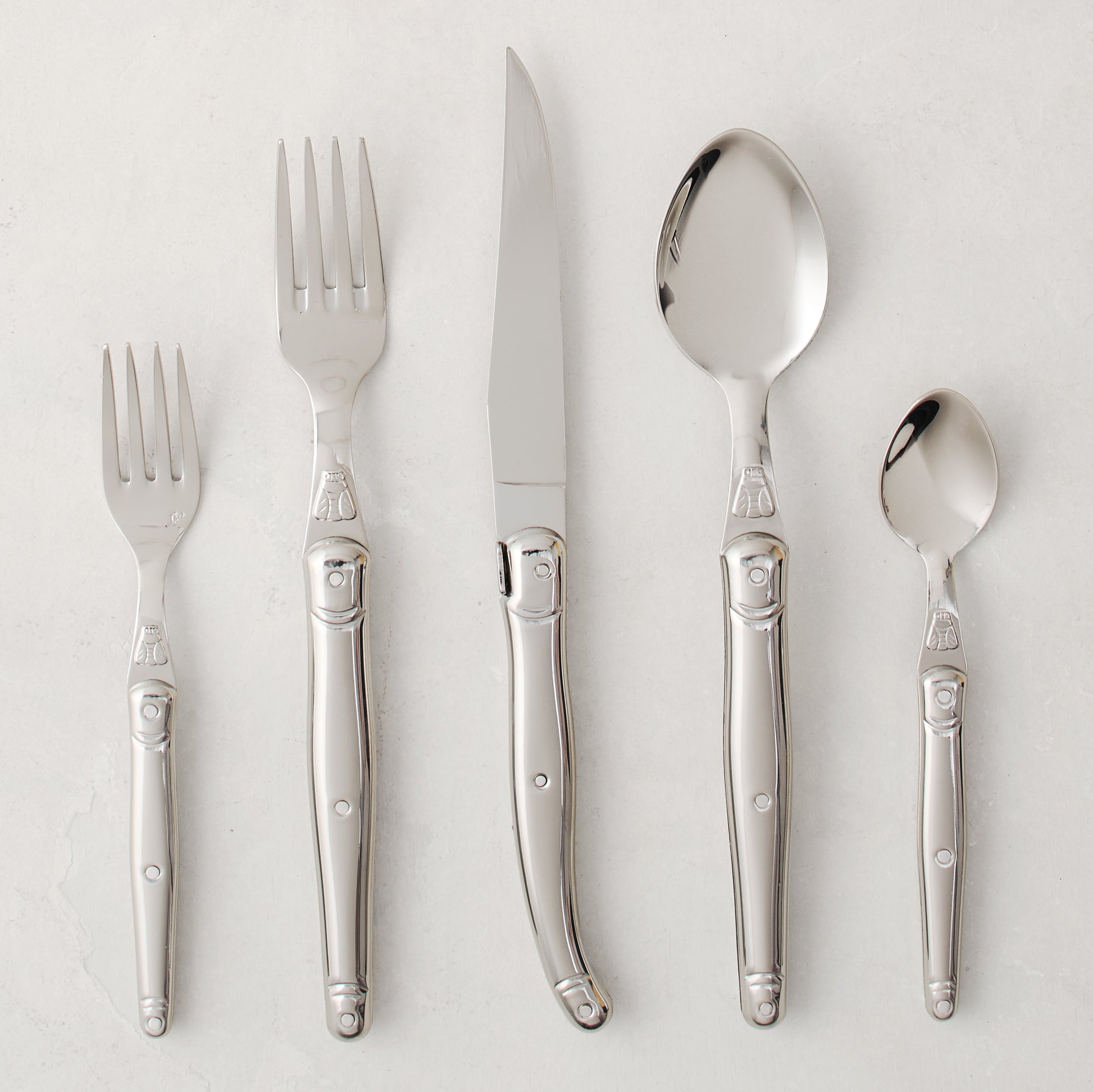 Jean Dubost Laguiole 5-piece stainless steel flatware set with iconic bee emblem.