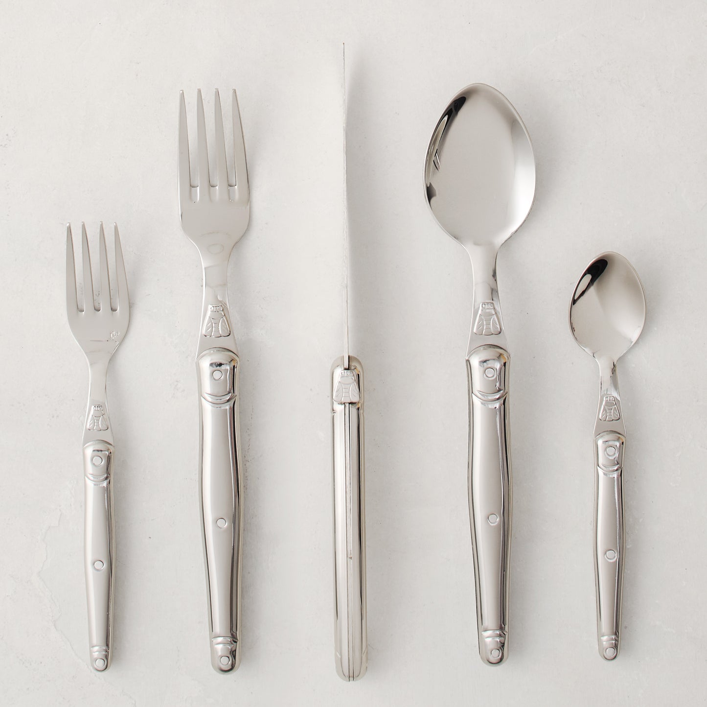 Jean Dubost Laguiole 5-piece stainless steel flatware set with iconic bee emblem.