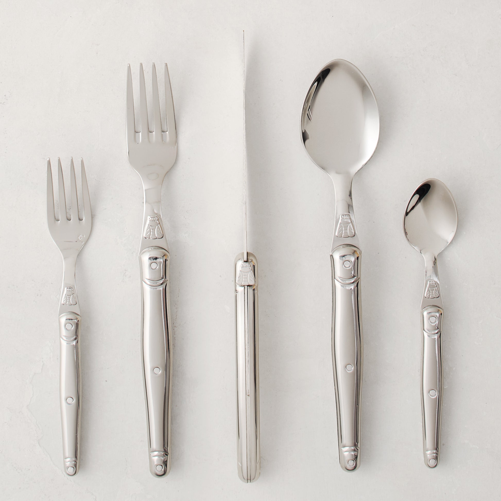 Jean Dubost Laguiole 5-piece stainless steel flatware set with iconic bee emblem.