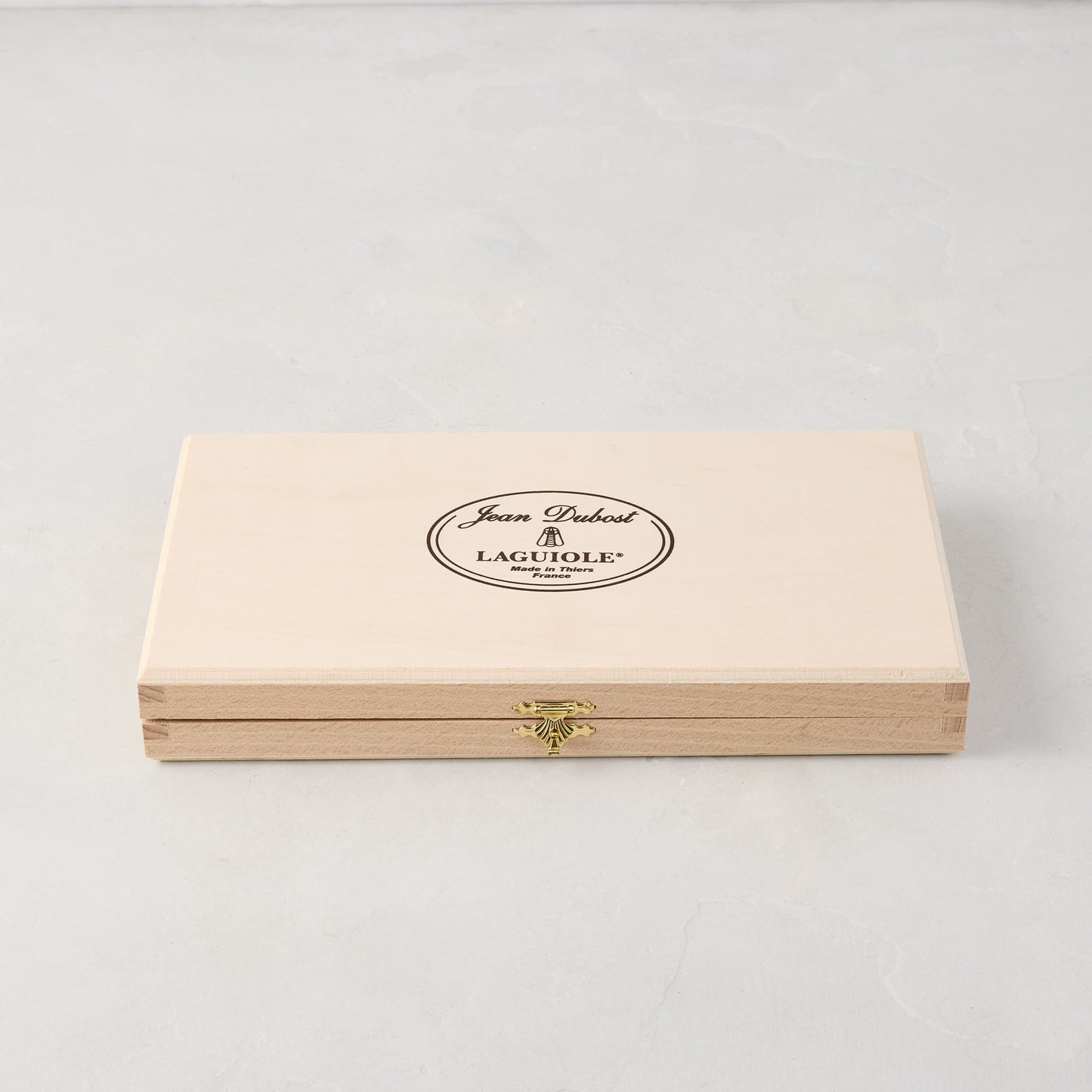 Jean Dubost Laguiole stainless steel table knives set in a light wooden storage box with a gold clasp.
