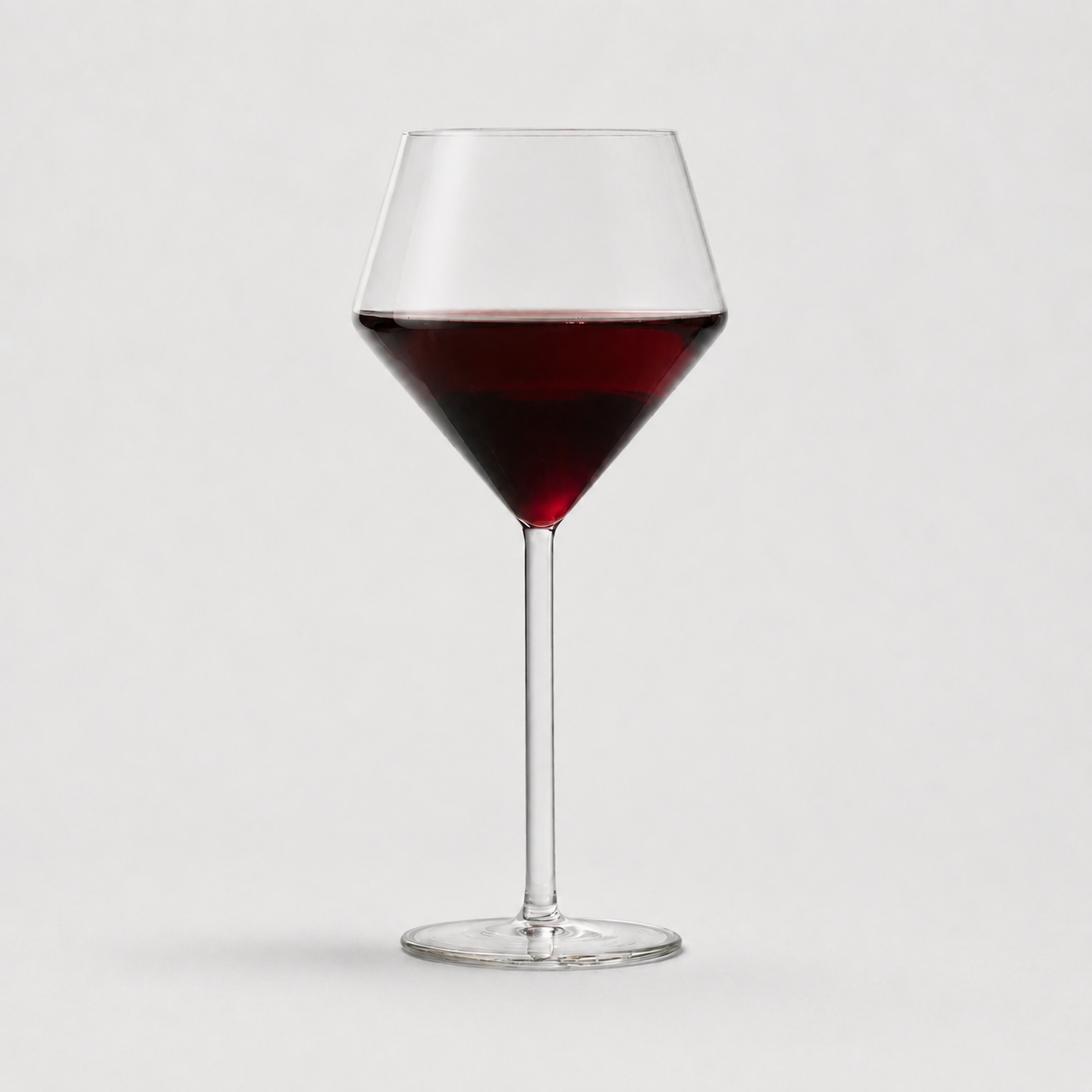 Juniper red wine glass with a modern geometric bowl and thin stem, filled with red wine, 17oz capacity.