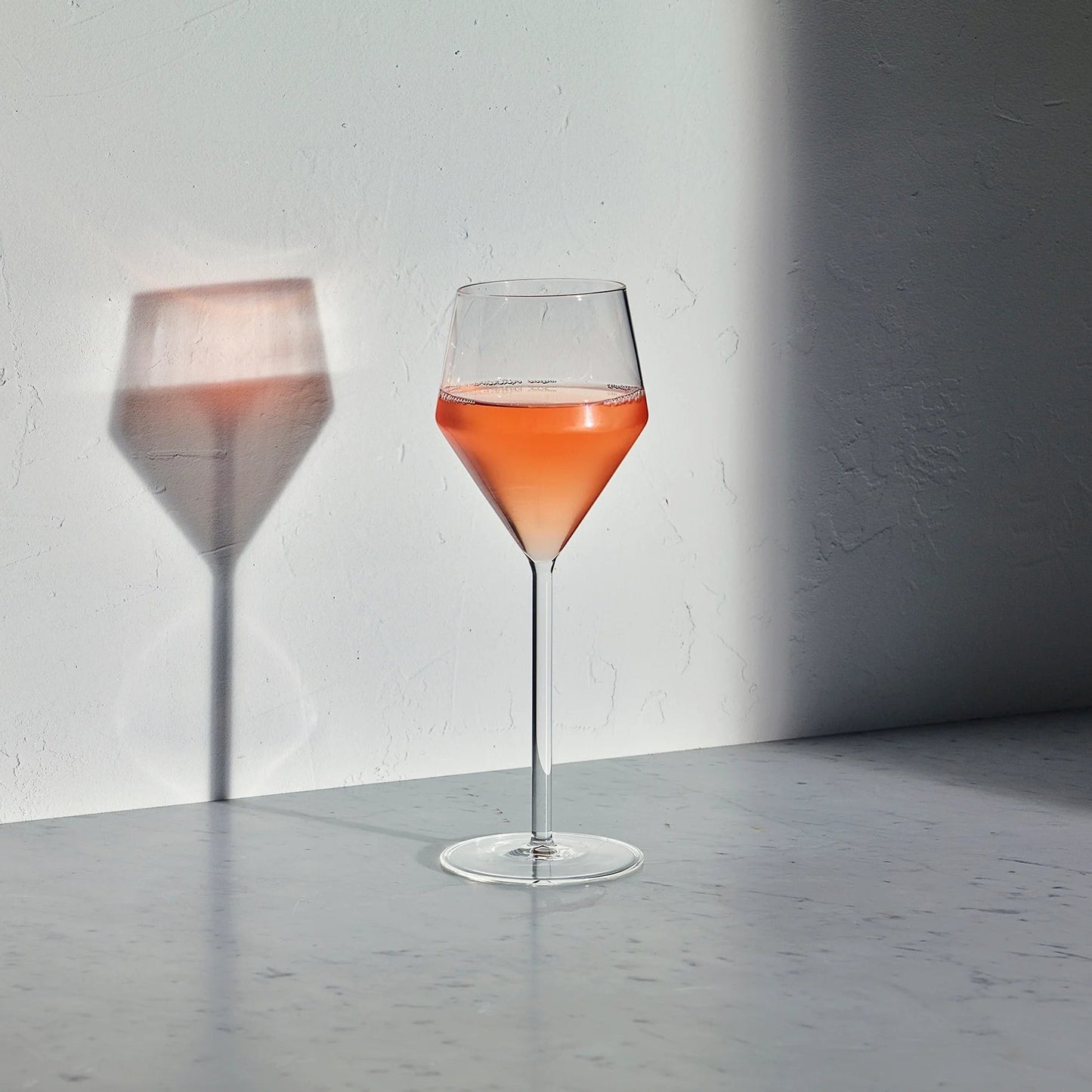 Hudson Grace Juniper white wine glass with a geometric silhouette and long stem filled with rose wine