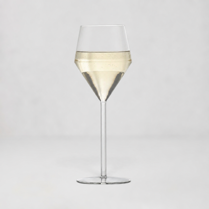 A clear glass wine glass with a wide bowl, a tapered middle section, and a long stem, shown on a light gray studio background. The glass is partially filled with a pale golden liquid.