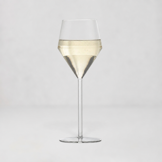 A clear glass wine glass with a wide bowl, a tapered middle section, and a long stem, shown on a light gray studio background. The glass is partially filled with a pale golden liquid.