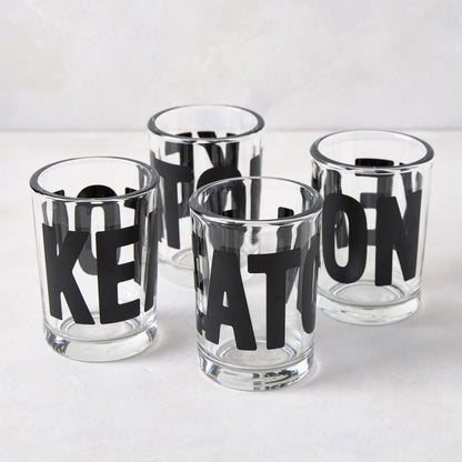 Four clear glass "Keaton" Everyday Wine Glasses with bold black lettering from Diane Keaton x Hudson Grace.
