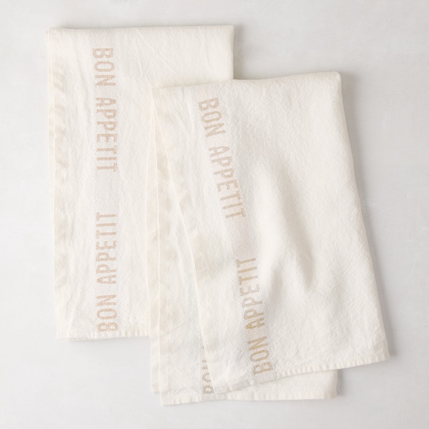 Set of 2 khaki linen hand towels with "BON APPETIT" text, folded on a white surface.