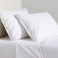 White organic cotton percale sheet set with khaki double scallop stitch embroidery on pillows and top sheet.