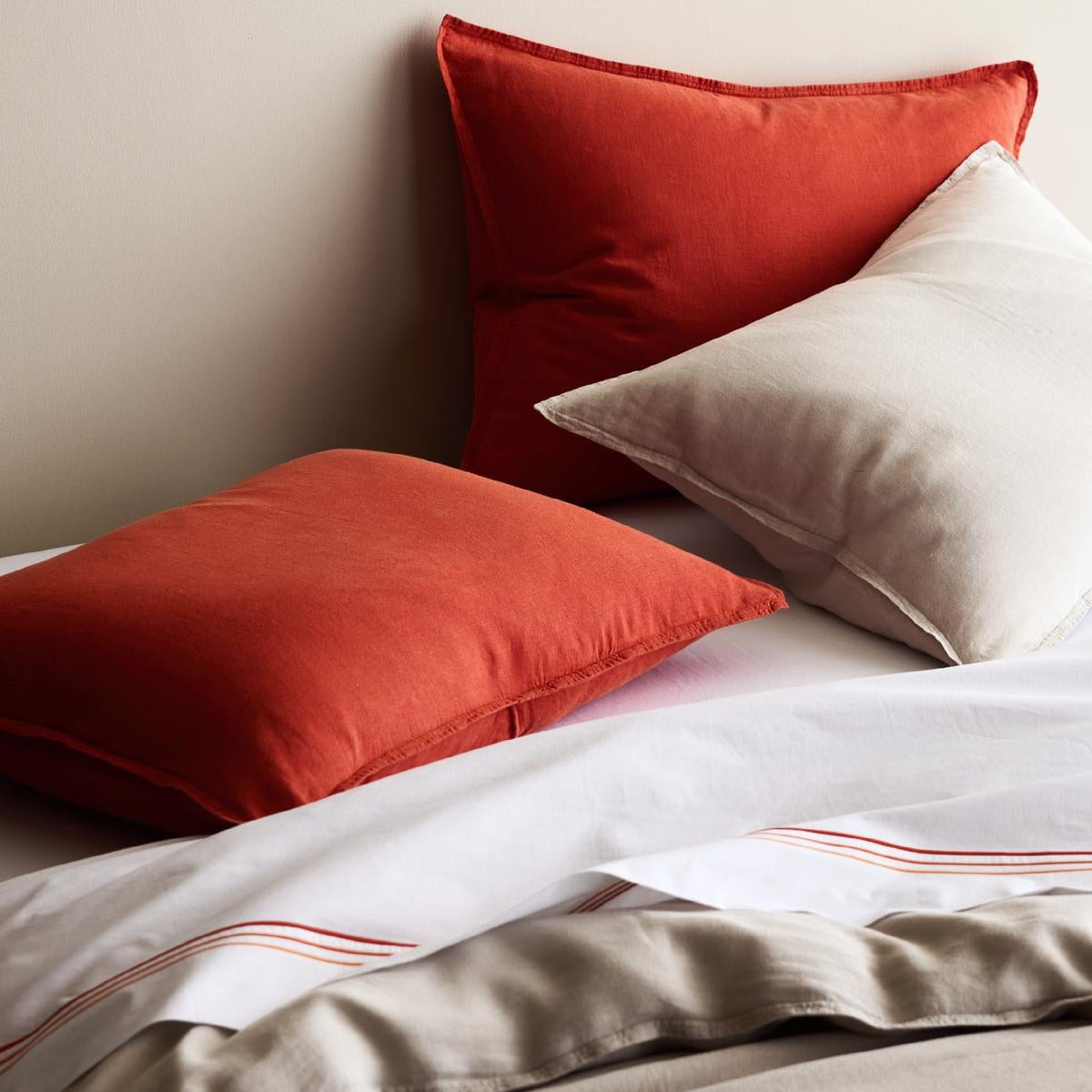 Khaki and terracotta washed linen pillows and duvet cover set with a relaxed, lived-in texture.