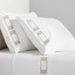 White percale sheet set with khaki embroidered Greek key border on pillows and flat sheet.