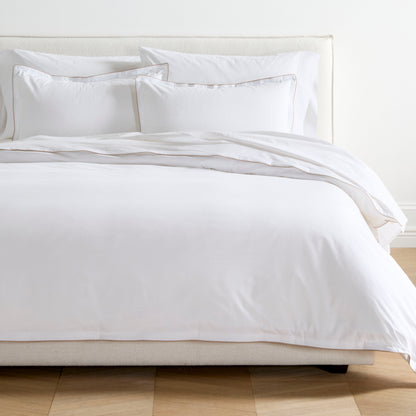 White percale duvet set with khaki piping and double-stitch detailing on a bed.