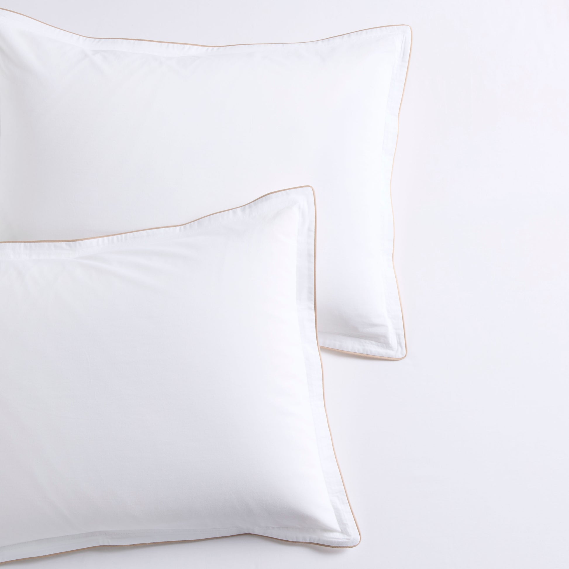 Two white percale pillow shams with khaki piping and subtle double-stitch detailing.