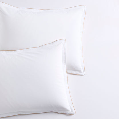 Two white percale pillow shams with khaki piping and subtle double-stitch detailing.