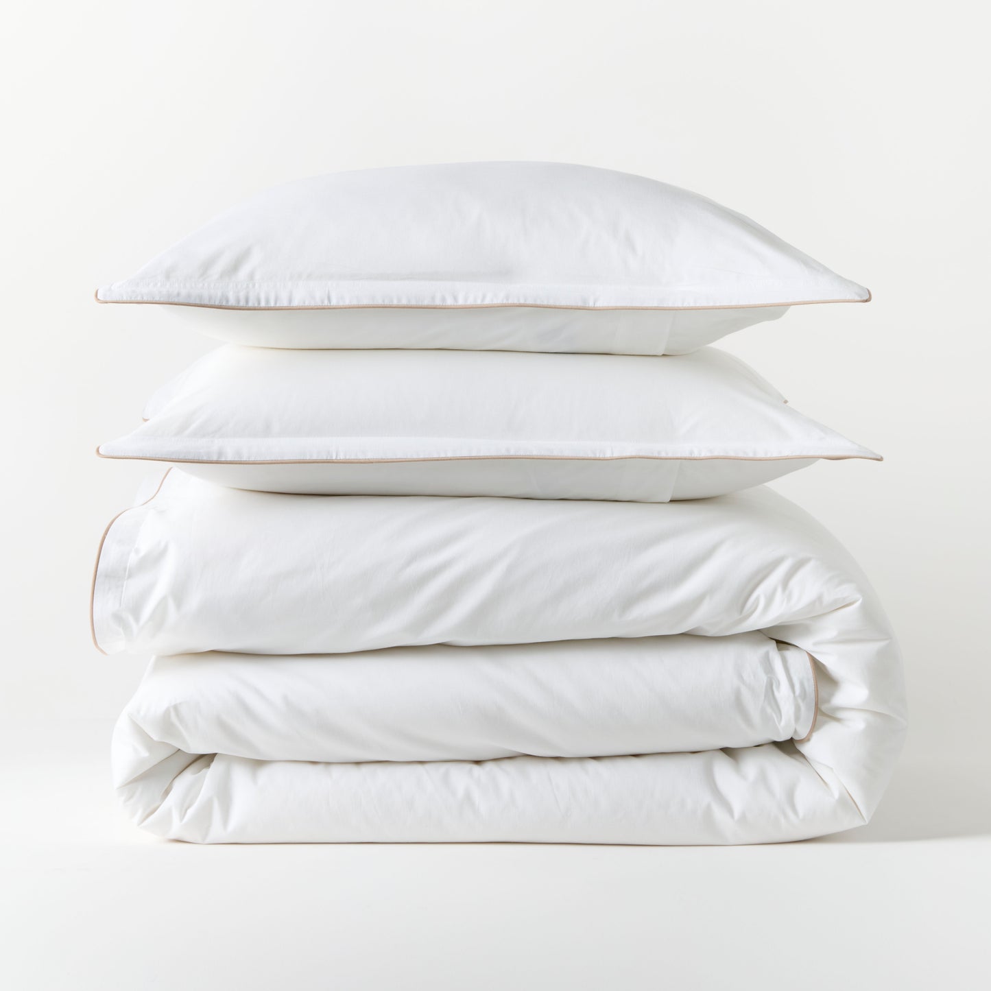 White percale duvet set with khaki piping, stacked neatly. Includes duvet cover and two shams.