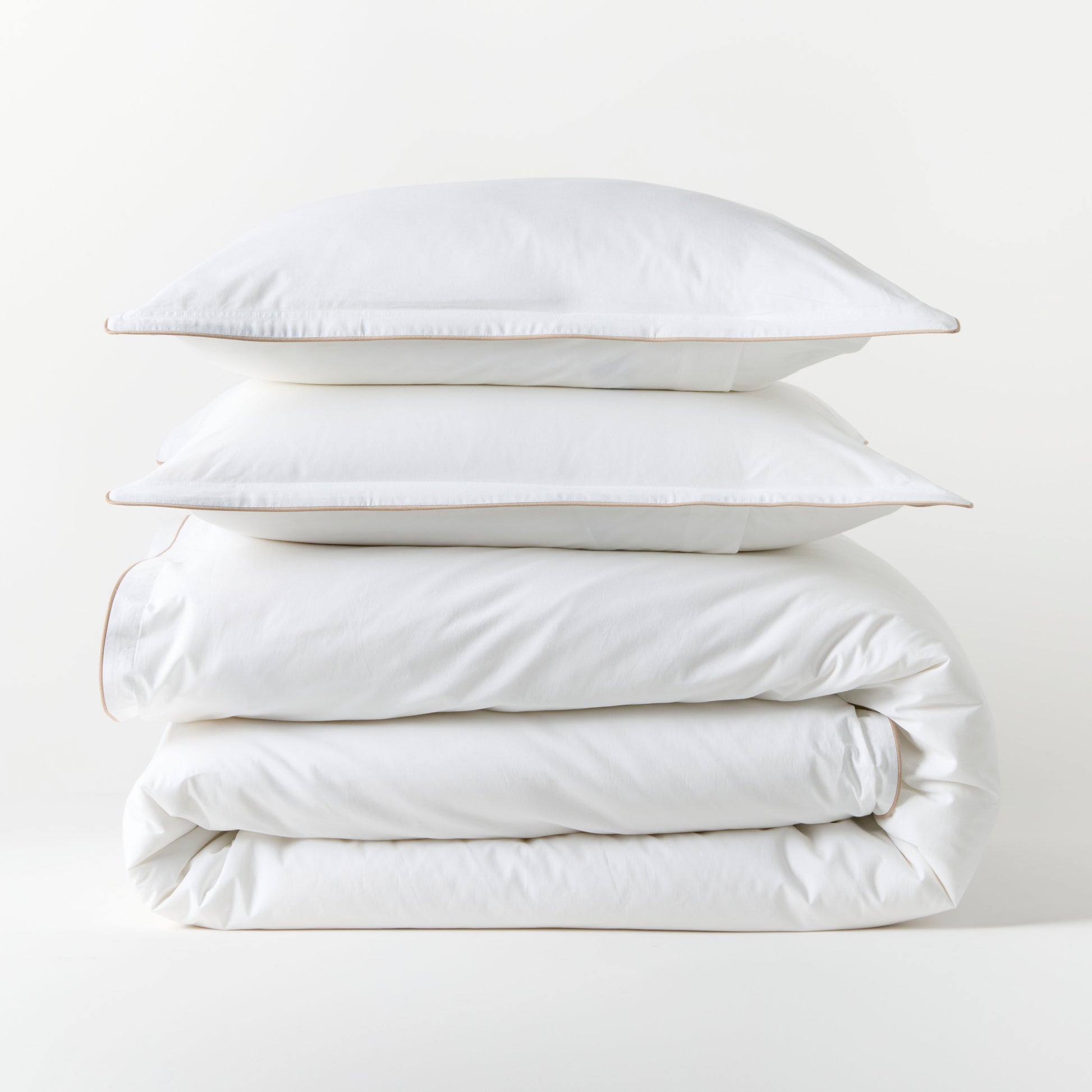 White percale duvet set with khaki piping, stacked neatly. Includes duvet cover and two shams.