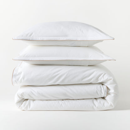 White percale duvet set with khaki piping, stacked neatly. Includes duvet cover and two shams.
