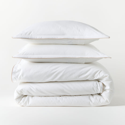 White percale duvet set with khaki piping, stacked neatly. Includes duvet cover and two shams.