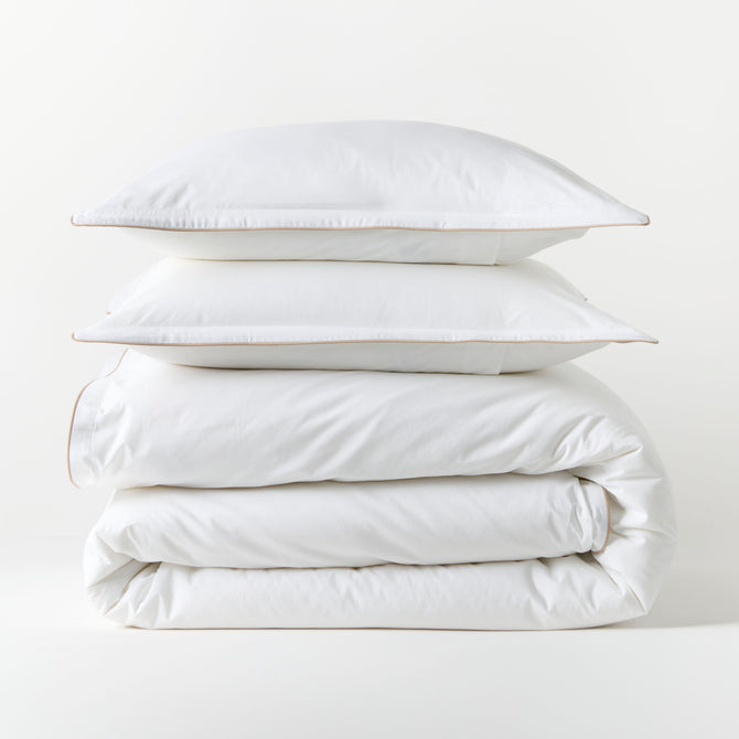 White percale duvet set with khaki piping, stacked neatly. Includes duvet cover and two shams.