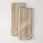 Set of 2 khaki striped French linen hand towels, folded on a white surface.