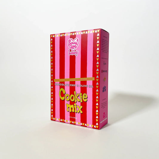 Knead Love chocolate chip cookie mix box with pink and red vertical stripes and a heart-patterned border.