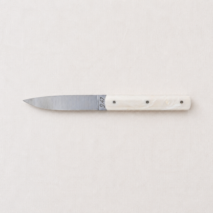 Perceval 9.47 stainless steel table knife with a sleek coffee creme Krion handle on a neutral fabric background.