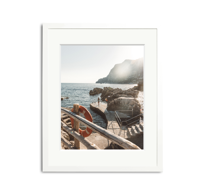 La Fontelina, Capri framed wall art print in a white wooden frame with a white mat, depicting a sunny Mediterranean coastline.