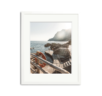 La Fontelina, Capri framed wall art print in a white wooden frame with a white mat, depicting a sunny Mediterranean coastline.