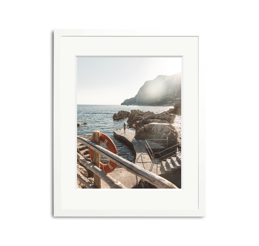 La Fontelina, Capri framed wall art print in a white wooden frame with a white mat, depicting a sunny Mediterranean coastline.