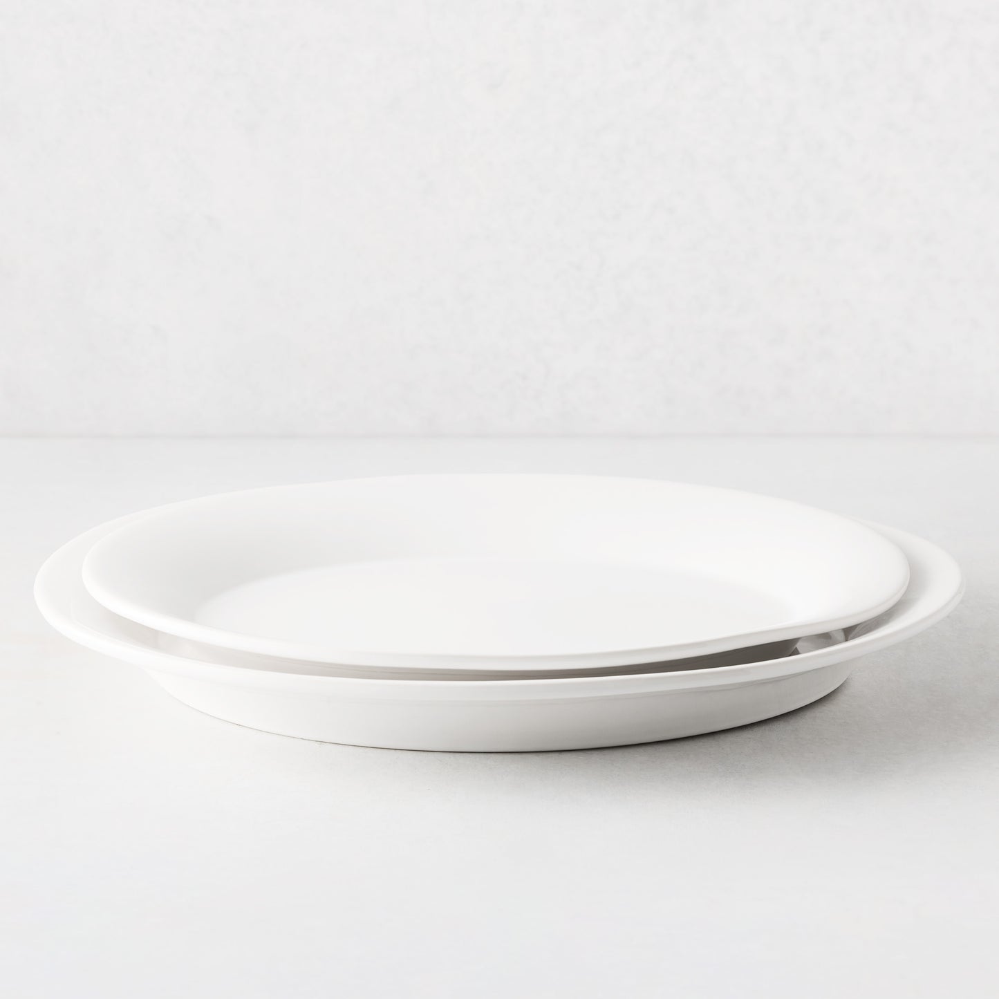 Two stacked Lagos white ceramic serving platters with raised edges.