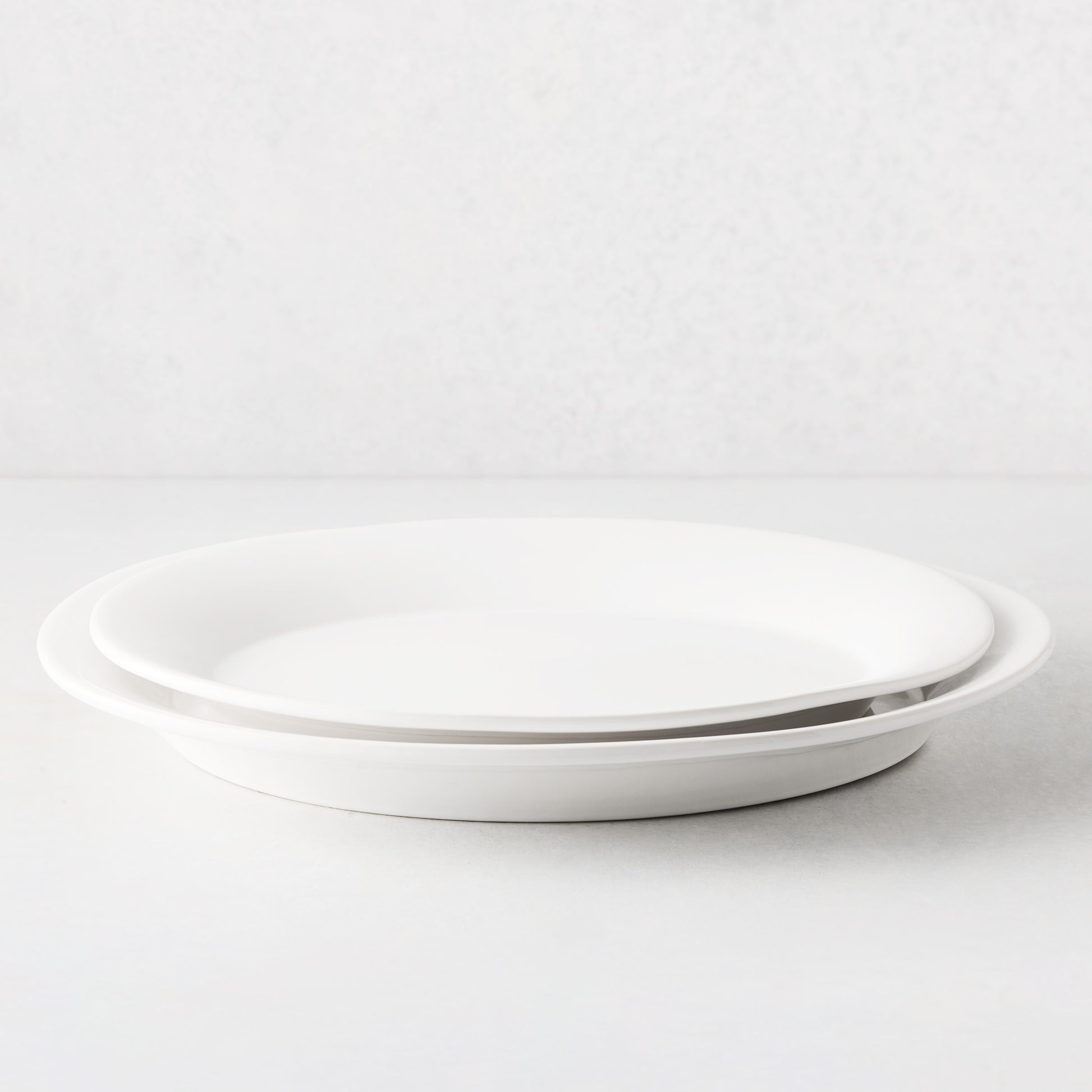Two stacked Lagos white ceramic serving platters with raised edges.