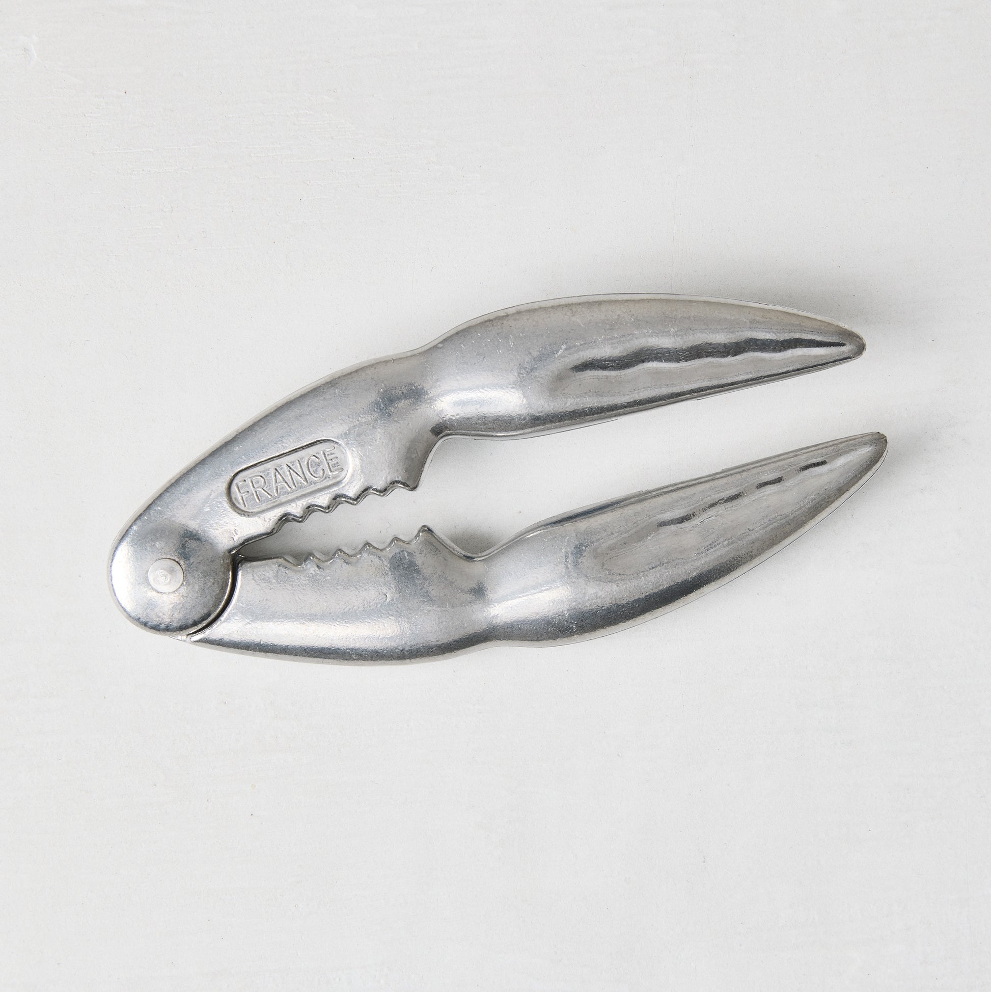 Laguiole Jean Dubost aluminum seafood crab cracker, claw-shaped, 5.5"L, with "FRANCE" embossed.