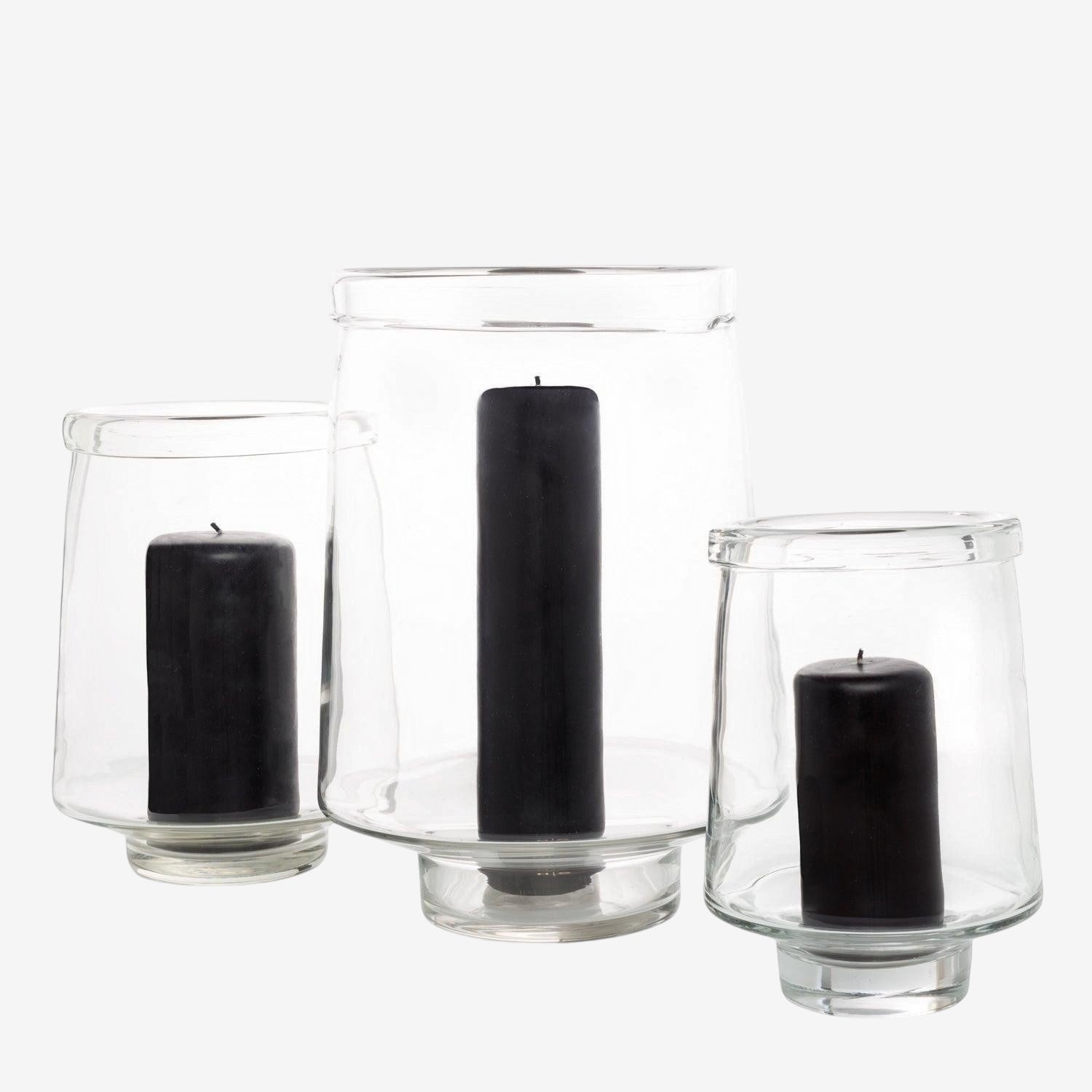 Three clear glass Antwerp hurricane candle holders, varying sizes, each with a black pillar candle.