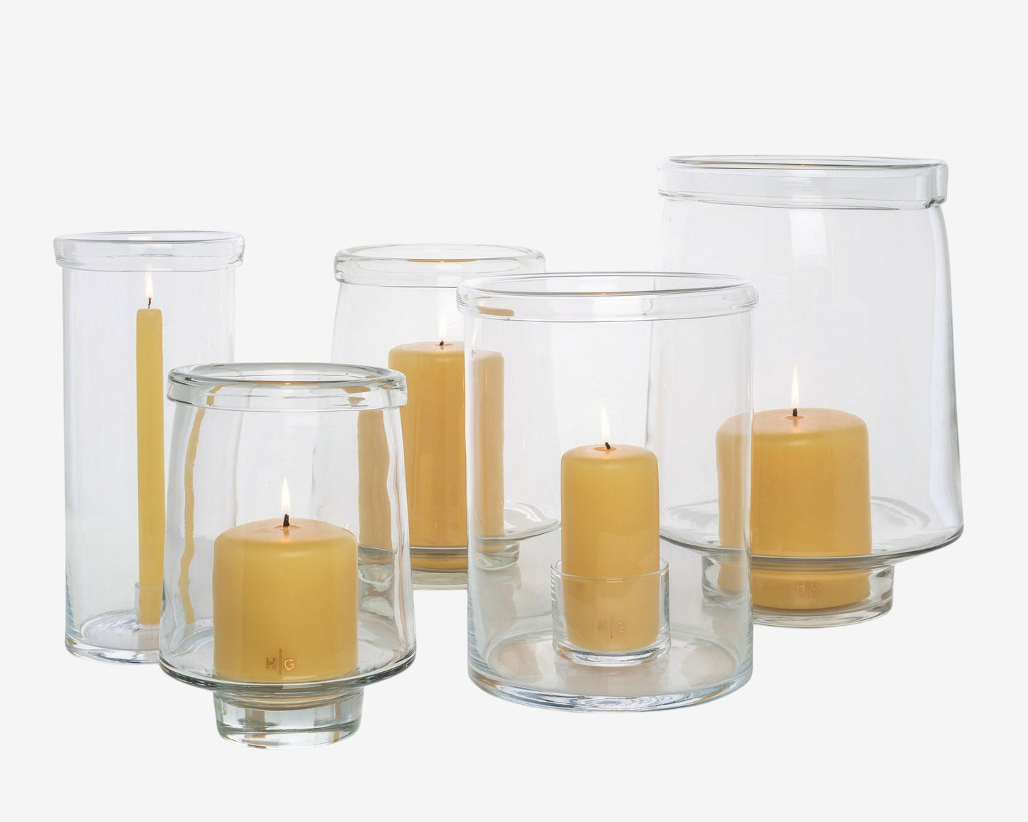 Clear glass Antwerp hurricane candle holders in three sizes, some with lit yellow pillar candles.