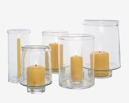 Clear glass Antwerp hurricane candle holders in three sizes, some with lit yellow pillar candles.