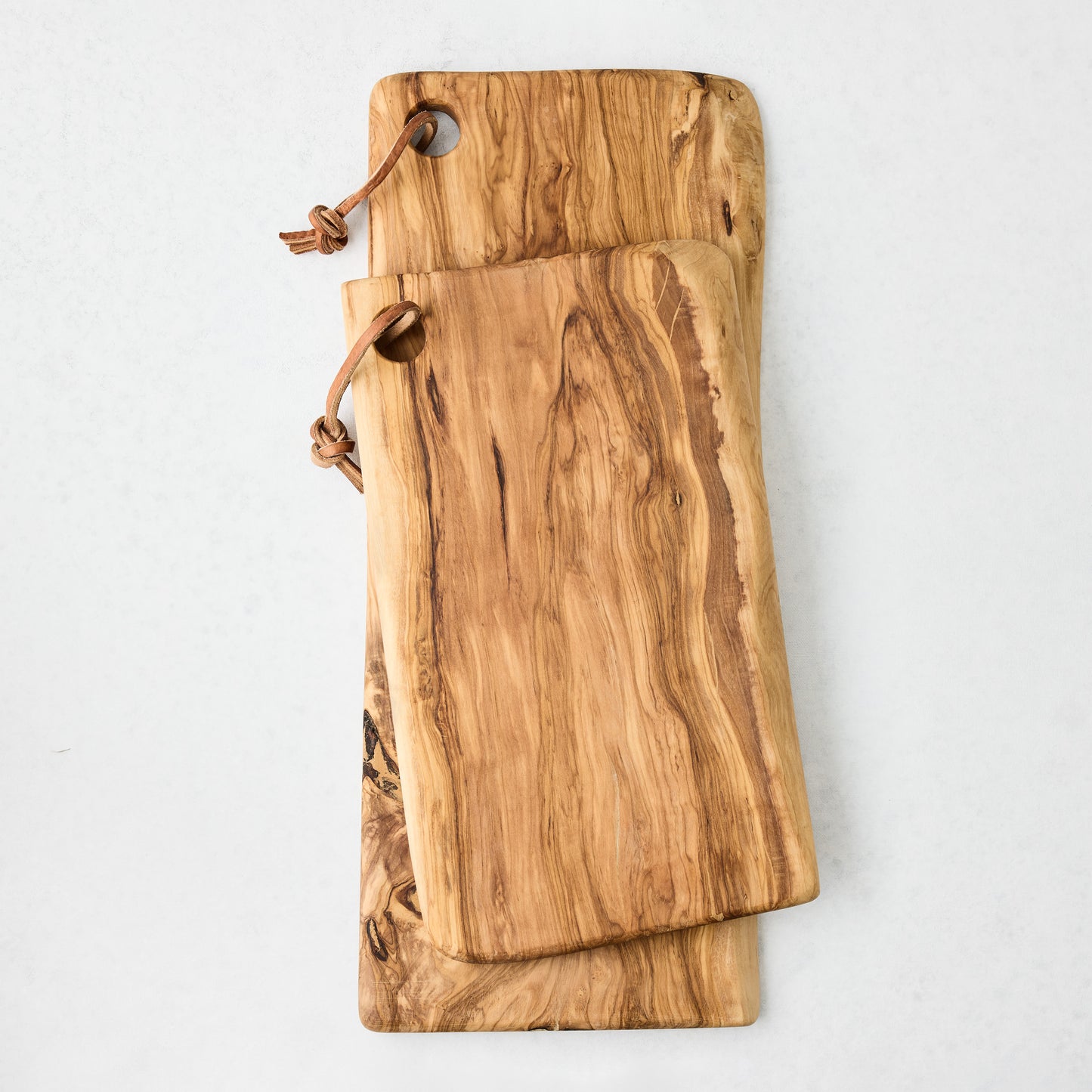 Two artisan olive wood rectangular serve boards with leather cords, one large, one smaller.