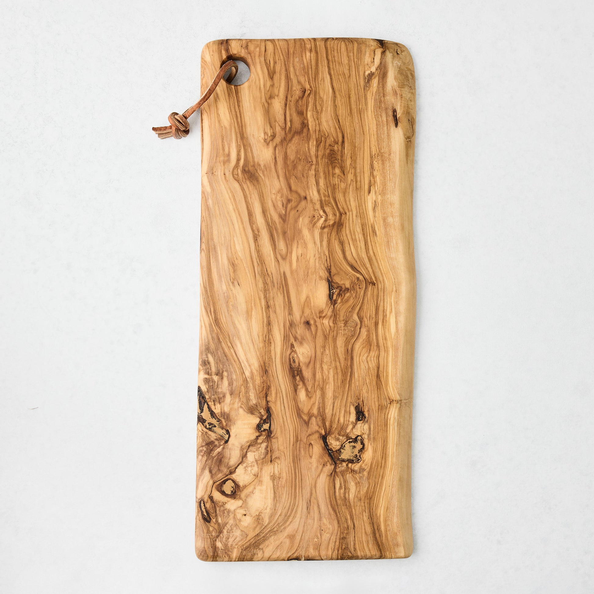 Large rectangular artisan olive wood serve board with natural grain and leather cord.